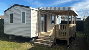 Une maison mobile dotée d’un porche couvert et d’une petite terrasse.