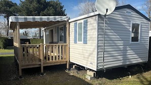 Une maison mobile dotée d’une terrasse en bois et d’une antenne parabolique.
