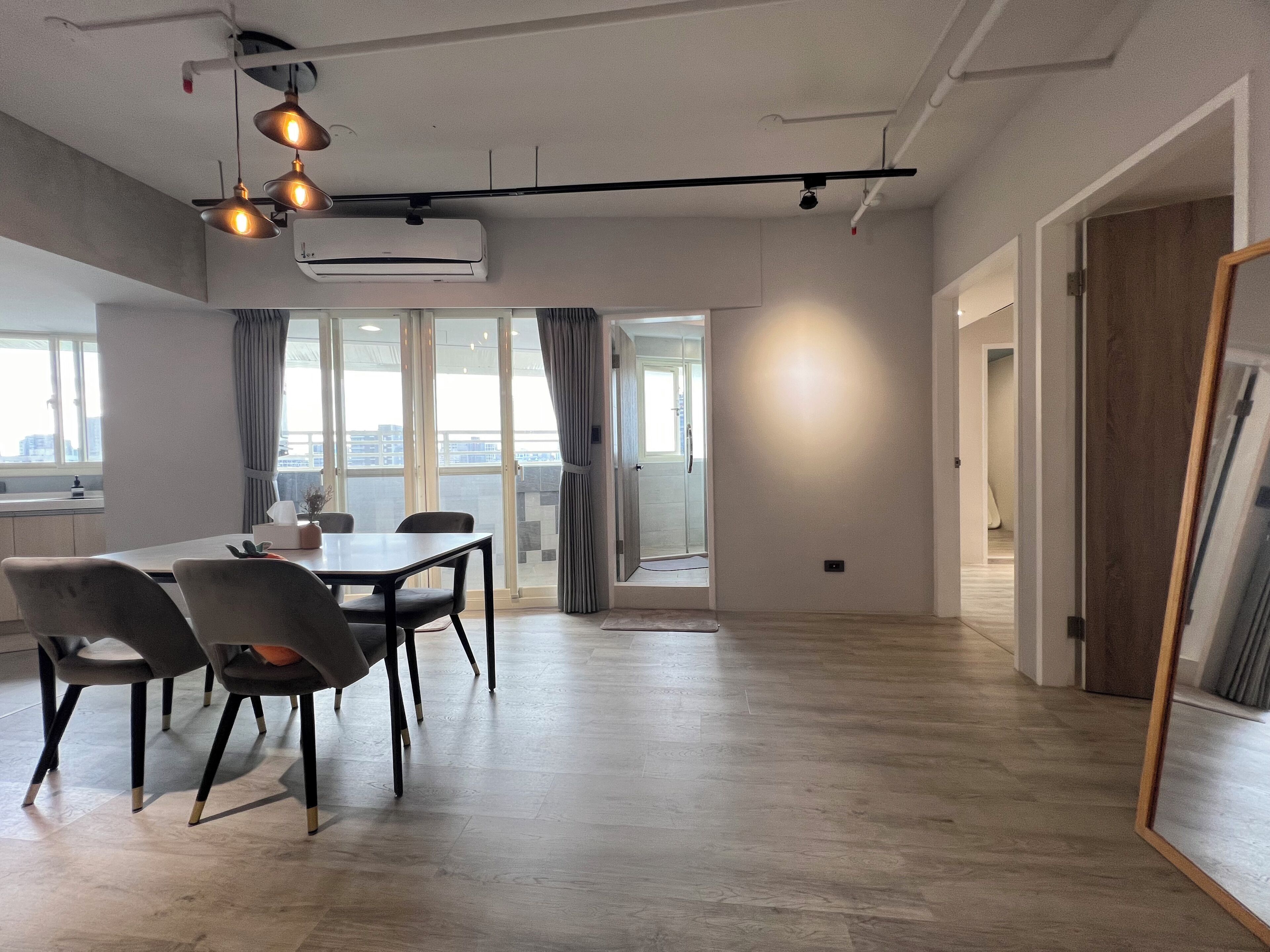 A spacious room with a dining table, chairs, and a large window with curtains.