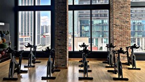 A gym with stationary bikes and a view of tall buildings through large windows. - Miami Downtown 27 floor Luxe Escape rooftop pool and jacuzzi (Miami)