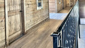 A wooden interior with a long corridor, wooden doors, and a metal railing. - Cozy Longhorn Suite on the River (Granbury)