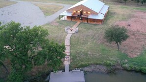 A large building with a covered patio area and a dock extending into a body of water. - Cozy Longhorn Suite on the River (Granbury)