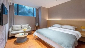 A modern hotel room with a bed, sofa, coffee table, and a TV mounted on the wall. - Sherlock Apartment (Riyuebei Theater) (Zhuhai)