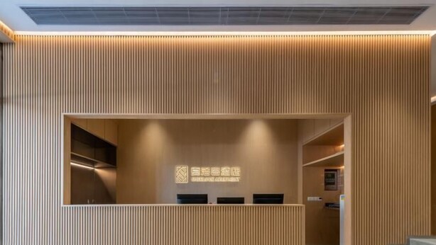 A reception area with a wooden panel wall, a reception desk, and a staircase leading to an upper level. - Sherlock Apartment (Riyuebei Theater) (Zhuhai)