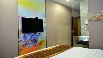 A hotel room with a bed, a television mounted on a colorful wall, and a bathtub.