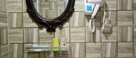 A bathroom with a mirror, a hairdryer, and a telephone on the wall.