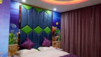 Quarto com cama, cabeceira com padrões geométricos e um mural na parede retratando paisagem subaquática.