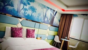 Camera d'hotel moderna con un grande letto, un murale, un tavolino, due sedie e una finestra con tende.