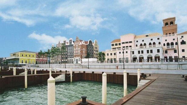 Una passeggiata lungomare con un pontile in legno, un ponte e edifici storici dall'architettura variegata.