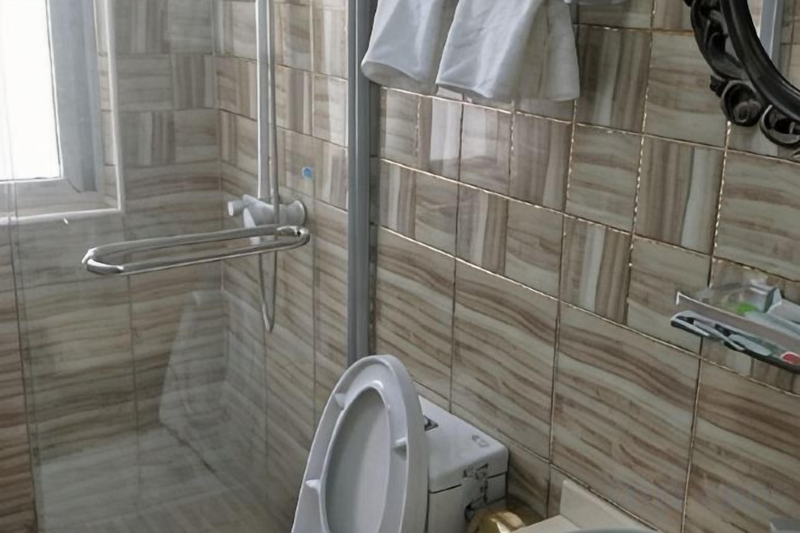 A bathroom with a toilet, a shower, and a glass-enclosed shower area.