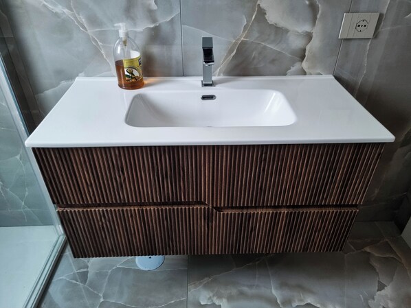 Une salle de bain avec un lavabo blanc, un flacon de savon liquide et un robinet moderne.