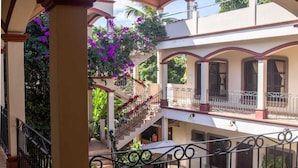 A multi-level courtyard with a central staircase, surrounded by balconies with railings, and potted plants. - Hotel Plaza YatBalam (Copan Ruinas)