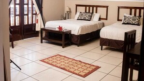 A hotel room with two beds, a ceiling fan, a window with curtains, and a tiled floor. - Hotel Plaza YatBalam (Copan Ruinas)