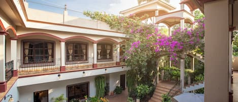 A multi-level courtyard with balconies, potted plants, and a pergola with flowering vines.