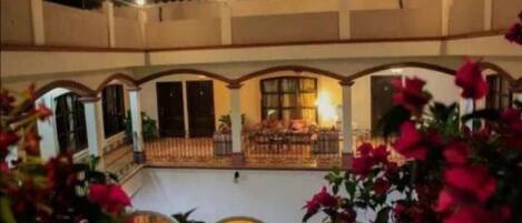A multi-level courtyard with arched balconies, potted plants, and string lights.