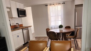 A compact living space with a kitchenette, a dining area, and a seating area with leather chairs. - Kenan Cottage in Whirlygig City, Unit B - 3 bd, 2 ba- 1300sf  - Downtown Wilson (Wilson)