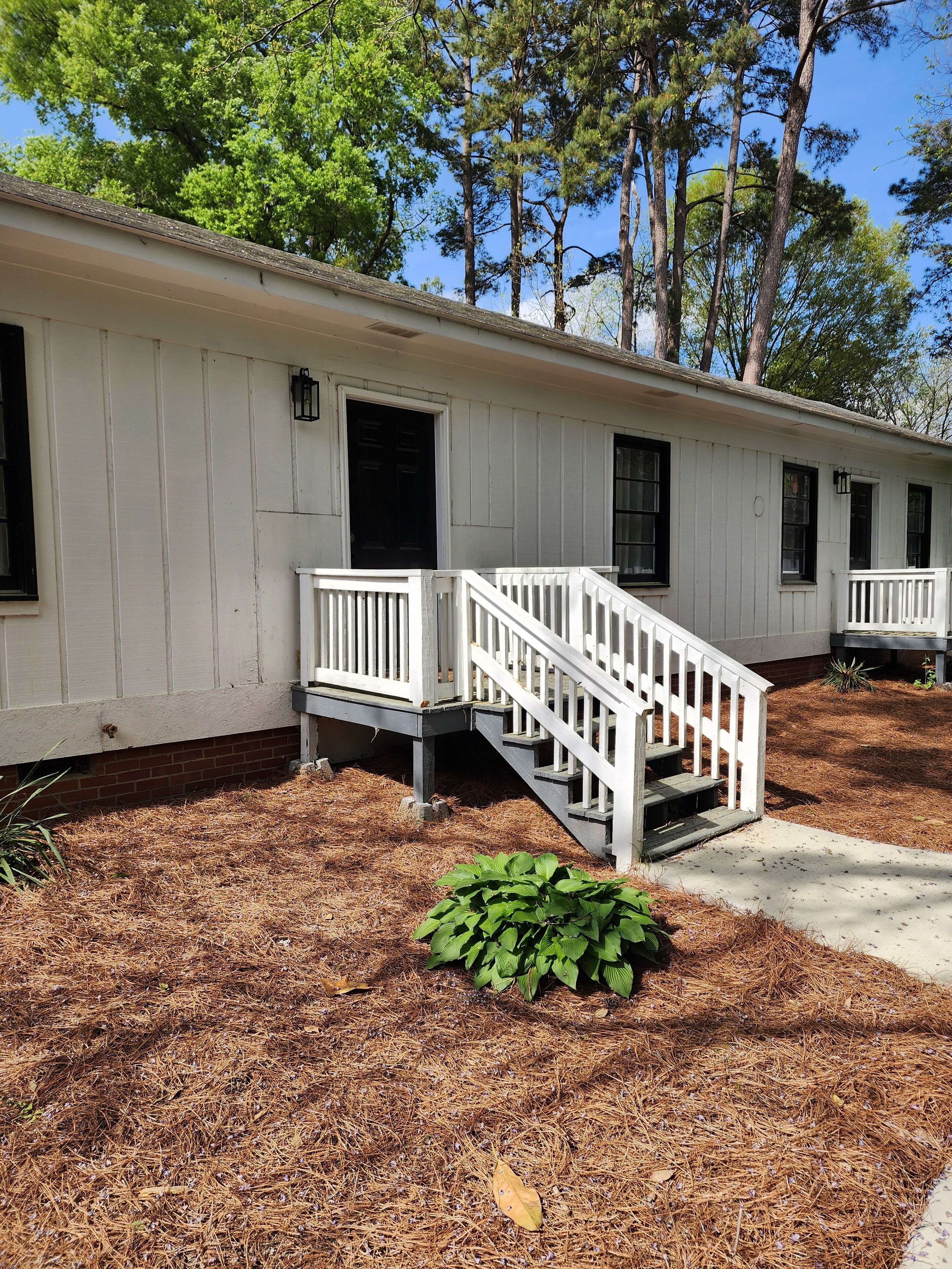 A white cabin with a front porch and a staircase leading to the entrance.