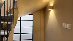 A staircase with a modern design, a wall-mounted light fixture, and a window with blinds. - Stylish Athenian Suite Near Acropolis - Balcony • AC • Walk to Everything! (Athens)
