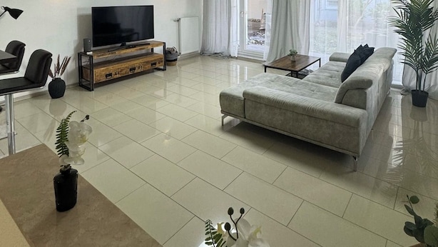A modern living room with a flat-screen TV, a sofa, a dining table, and a coffee table. - C&V: 3 PP - 2 rooms +WLAN+Smart-TV+Boxspringbed (Kaiserslautern)