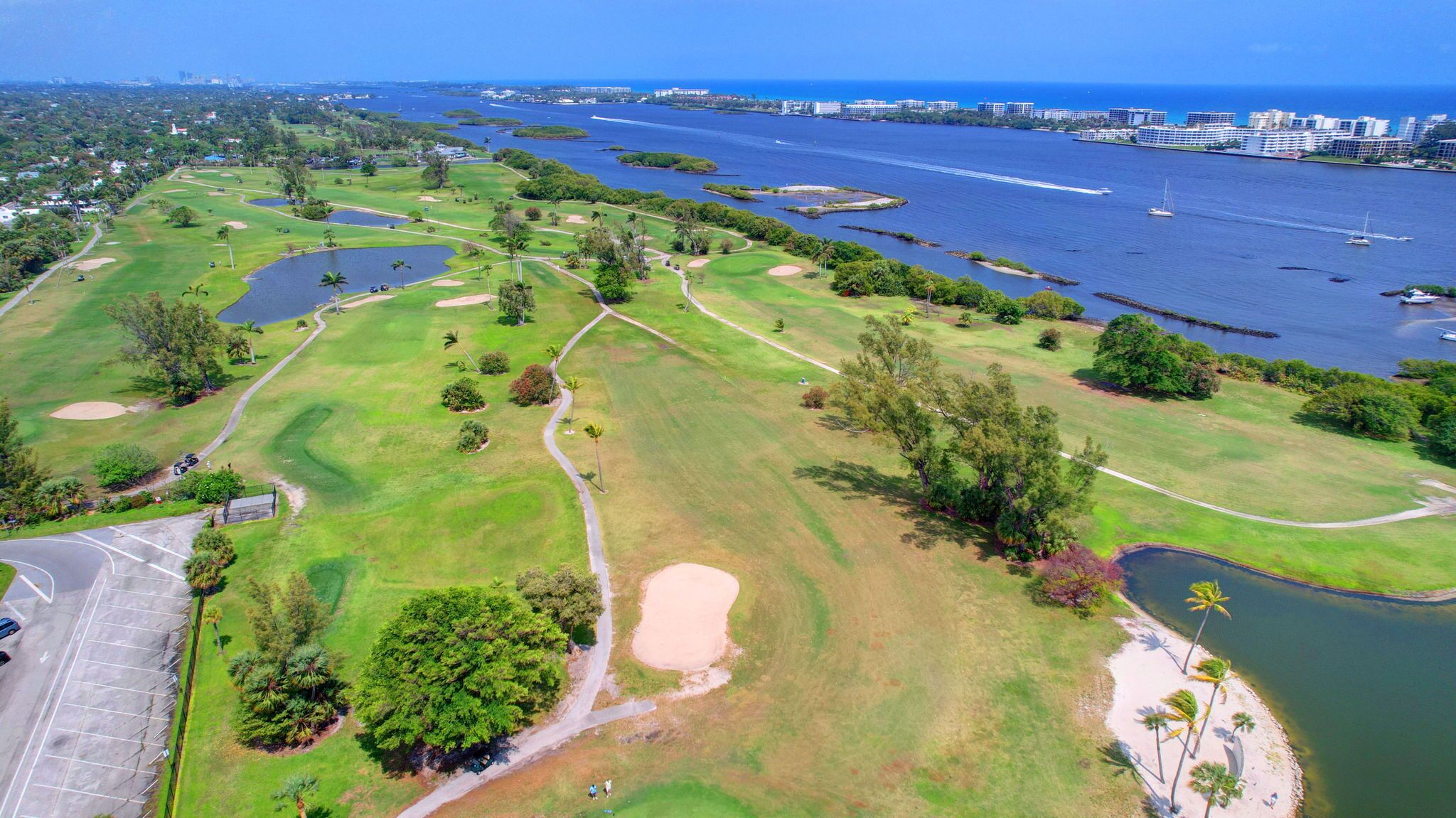 Vue aérienne d’un terrain de golf avec un port de plaisance et le profil de la ville en arrière-plan.