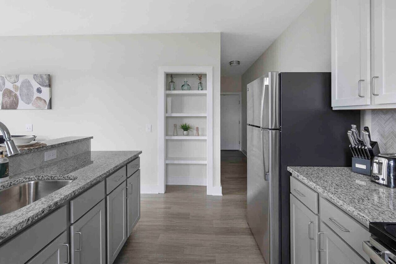A modern kitchen with granite countertops, stainless steel appliances, and white cabinetry.