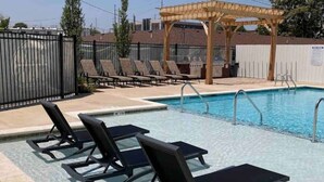 A swimming pool with lounge chairs and a pergola. - Modern Penthouse Condo with Panoramic City View (Nashville)