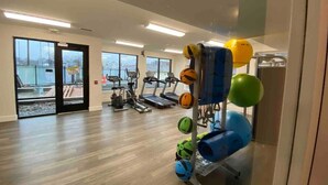 A gym with exercise equipment, treadmills, and a view of the city through large windows. - Modern Penthouse Condo with Panoramic City View (Nashville)