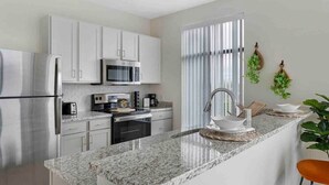 A modern kitchen with white cabinets, stainless steel appliances, and a granite countertop. - Modern Penthouse Condo with Panoramic City View (Nashville)