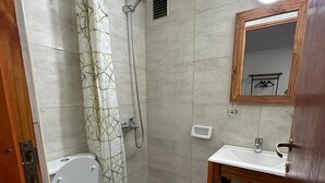 Une petite salle de bain avec des toilettes, une douche et un lavabo.