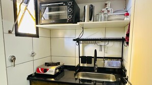 Une cuisine compacte équipée d’un four encastré, d’une machine à café et d’un évier.