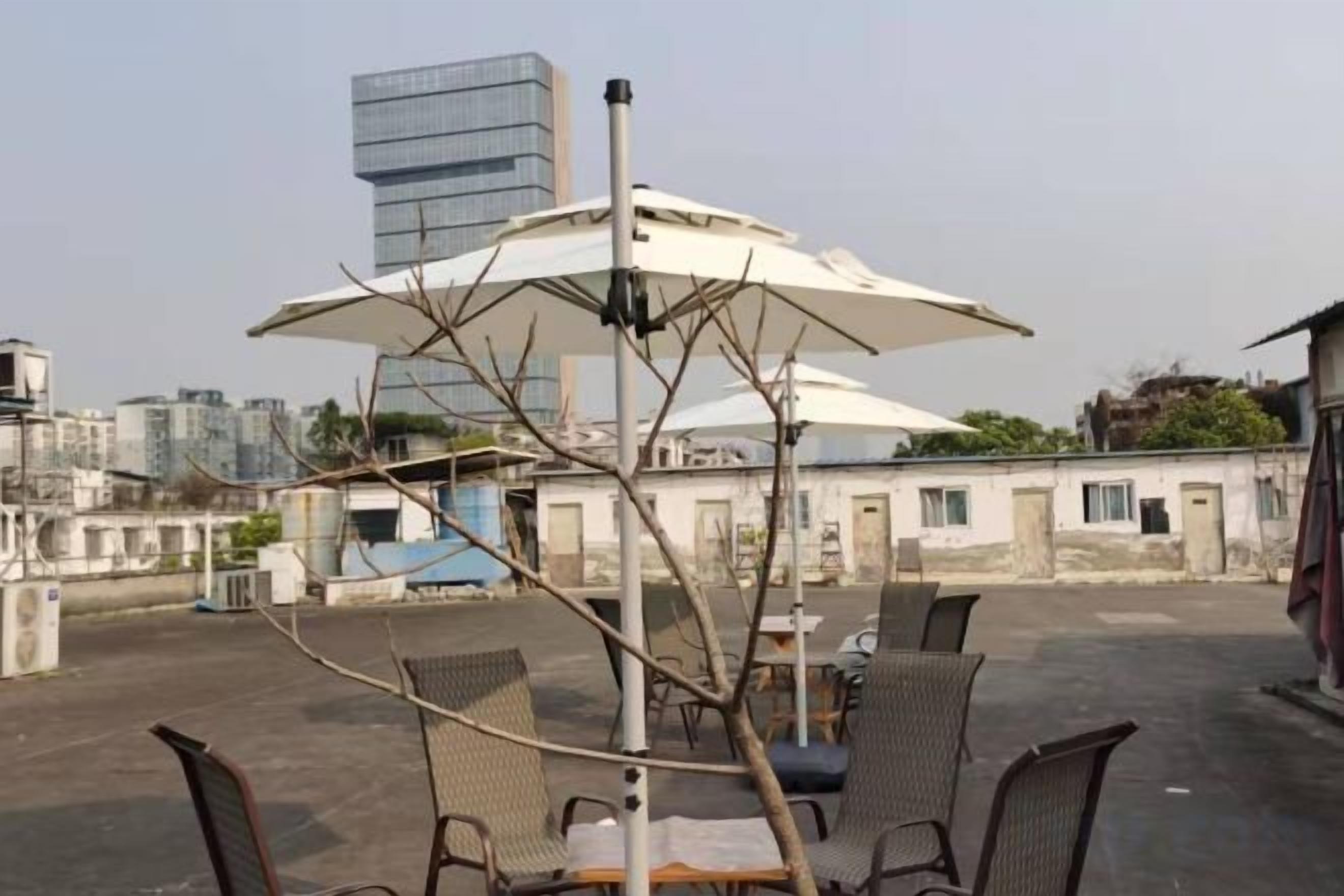 A rooftop terrace with outdoor seating, a table, and a view of the cityscape.