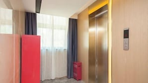 A modern elevator with a digital display, a red storage unit, and a window with curtains. - Lavande Hotel (Beijing)