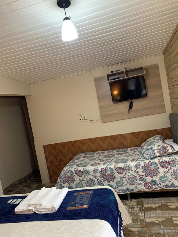 Ett hotellrum med en säng, en tv som är monterad på väggen och en taklampa.