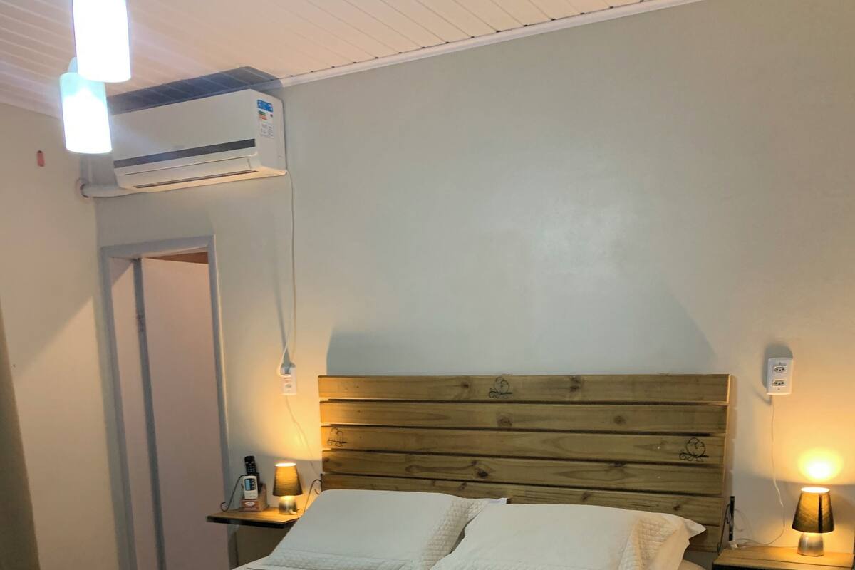 A neatly made bed with a wooden headboard, two bedside lamps, and a small bedside table with a lamp.