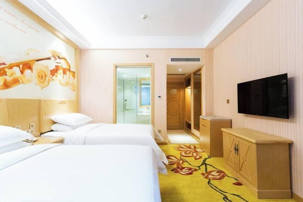 Een hotelkamer met twee bedden, een televisie, een kledingkast en een kamerbreed tapijt met bloemenmotief.