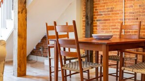 Un espace repas avec un mur en briques, des chaises en bois et une table.