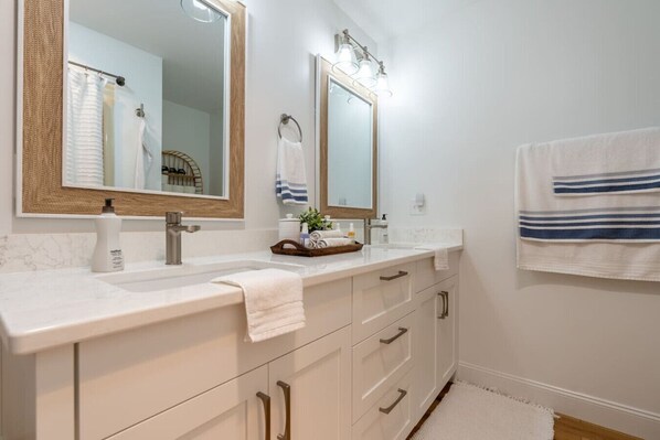Une salle de bain avec deux lavabos, un grand miroir et un porte-serviettes.