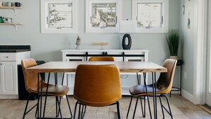 Een eetgedeelte met een witte tafel, vier stoelen en een decoratieve lamp.