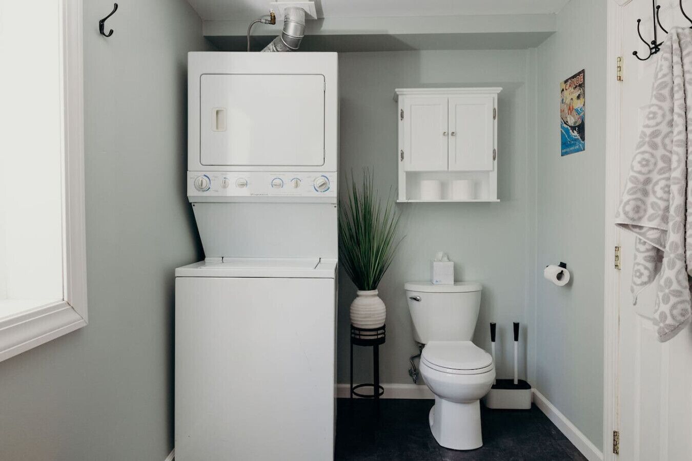 A compact bathroom with a washing machine, toilet, and a cabinet.