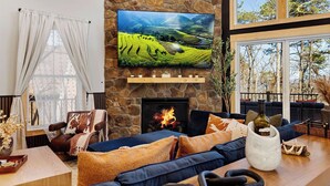 Een gezellige woonkamer met een stenen open haard, een grote flatscreen televisie en een comfortabele zithoek.