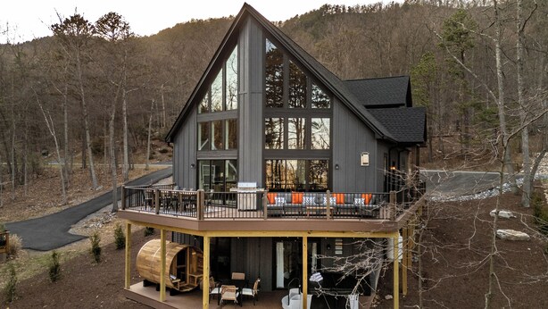 Een moderne hut met een ruim balkon, een houten terras en een sauna.