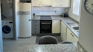 A compact kitchen with white cabinets, a built-in oven, a sink, and a granite countertop. - Modern apartment 5 minutes from La Sella Golf Course (La Sella)