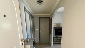 A hallway with a white door, a closed door, and a kitchen area in the background. - Modern apartment 5 minutes from La Sella Golf Course (La Sella)