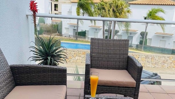 A balcony with wicker furniture, a glass table, and a breakfast setting including croissants and orange juice. - Modern apartment 5 minutes from La Sella Golf Course (La Sella)