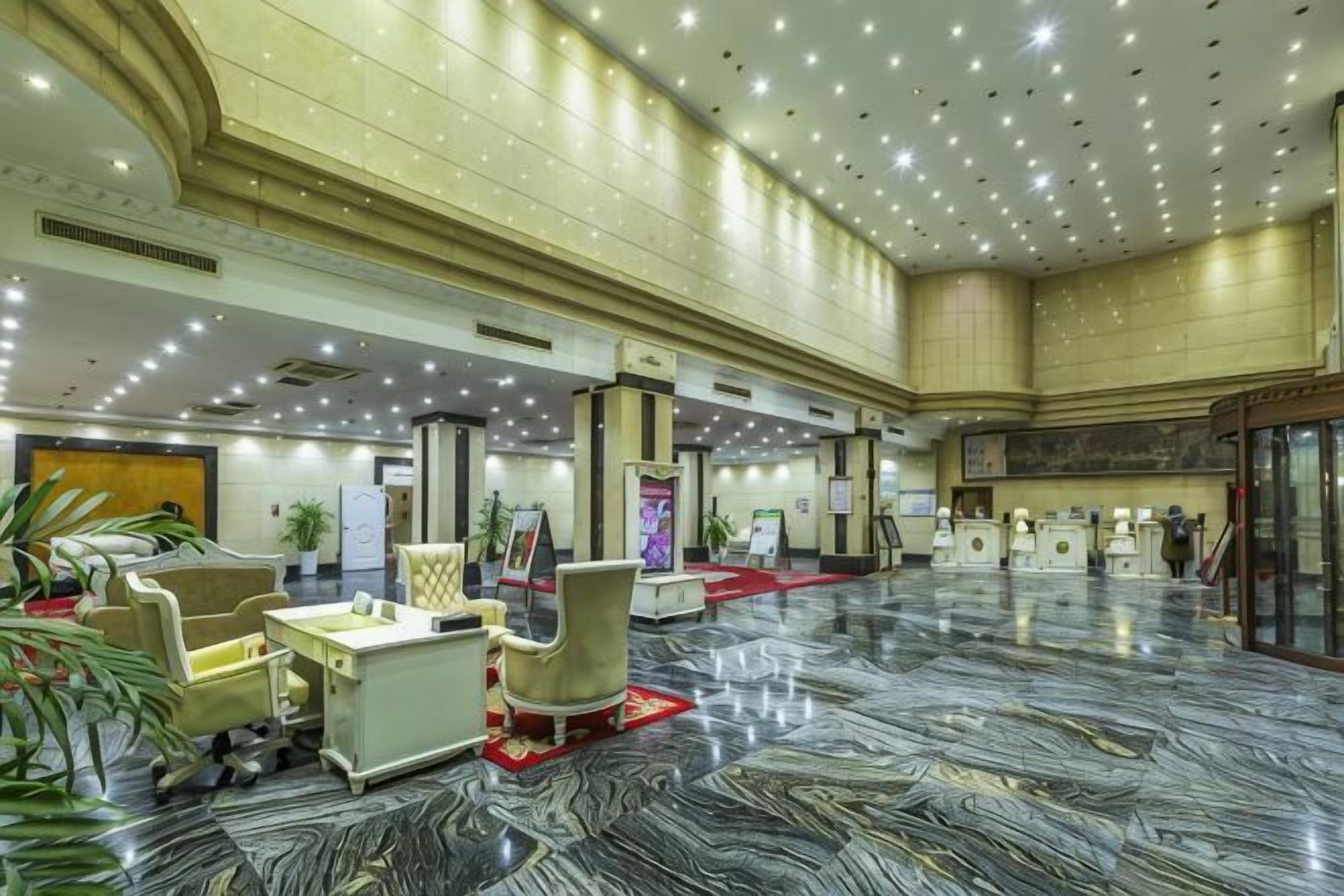 A spacious lobby with a marble floor, seating areas, and a reception desk.