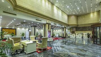 A spacious lobby with a marble floor, seating areas, and a reception desk.