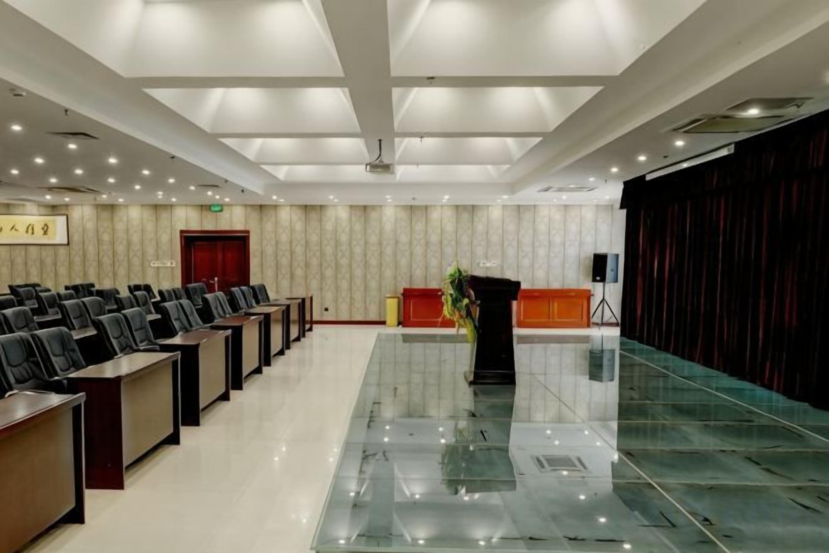 A conference room with rows of chairs, a podium, and a stage area.