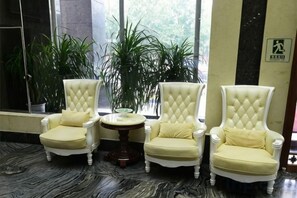 A seating area with three upholstered chairs and a small round table, surrounded by potted plants. - Jiatai Hotel (Binzhou)