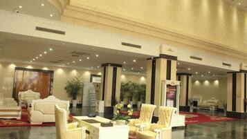 A lobby with a marble floor, plush seating, and a red carpet.