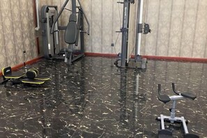 A gym with exercise equipment, including a bench and weights. - Jiatai Hotel (Binzhou)